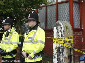Police officers guard a house in Manchester, England, following raids and arrests of terror suspects.