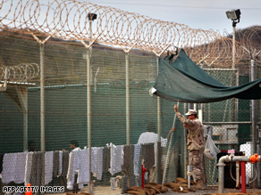 A guard leans on a fence talking to a detainee at Guantanamo earlier this year.