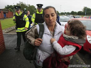 A Romanian woman and her child are escorted by police in Belfast on Wednesday.