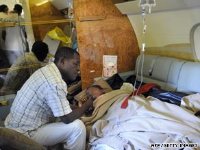Bahia Bakari holds her father's hand as she lies on a stretcher in a plane after landing in France.