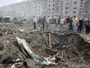 People stand near a crater caused by the blast in Nazran.