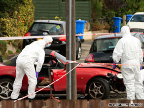 Bomb disposal experts examine a car Friday after a blast beneath it in east Belfast, Northern Ireland.