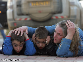 An Israeli woman and her two children take cover during a rocket attack alert near Kfar Aza.
