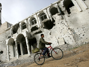 A Palestinian rides his bike near a mosque damaged during the attack by Israel on Gaza.