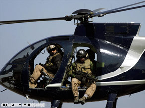 Heavily armed Blackwater guards scan downtown Baghdad, Iraq, from a helicopter in 2003.