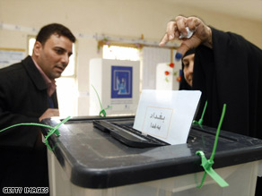 Two Iraqi men head to separate voting booths to pick a candidate.
