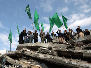 Hamas supporters stand on the rubble of a building hit by an Israeli strike that killed Hamas' interior minister.