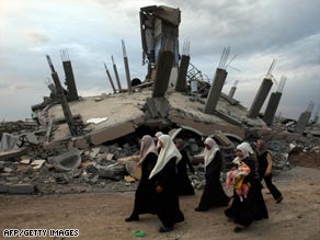 Palestinian women walk past a building destroyed during Israel's campaign in Gaza.