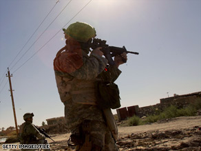 U.S. troops based at Camp Liberty near Baghdad, Iraq, wait while a robot disarms a roadside bomb in 2005.