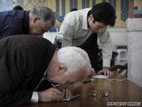 Iranians walk past campaign posters in Tehran ahead of Friday's ballot.