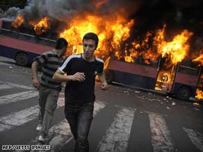 Moussavi supporters run past a burning bus in Tehran on Saturday.