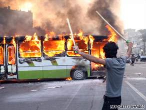 A demonstrator exults Saturday as flames consume a bus on a street in Tehran.