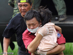 A rescue worker carries a child on Tuesday who survived flooding in southern Taiwan.