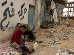 Palestinians sit next to Israeli-bombed buildings in Rafah, in the Gaza Strip.