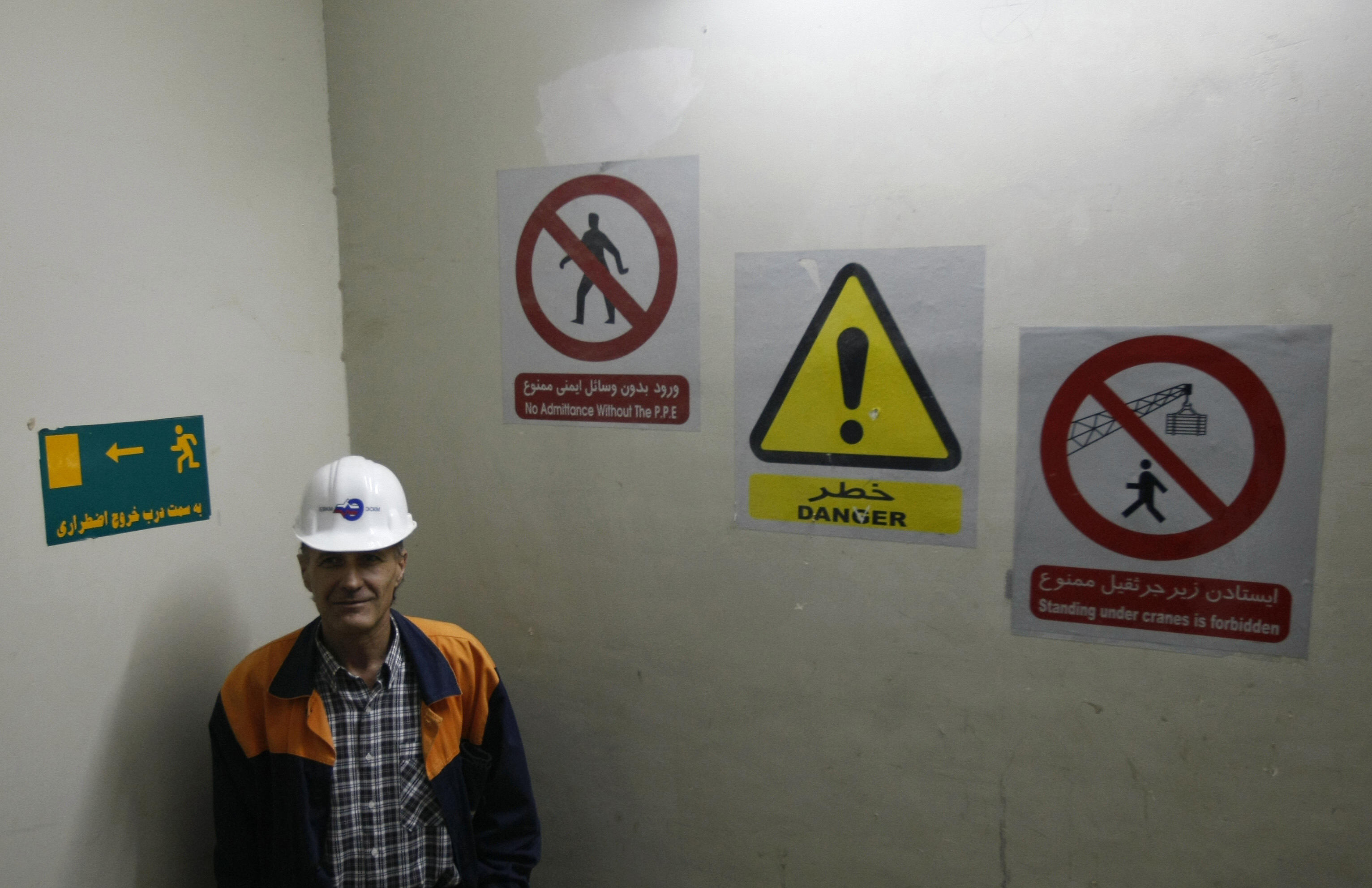 BEHROUZ MEHRI/AFP/Getty Images. A Russian technician stands under warning signs at the Bushehr nuclear power.