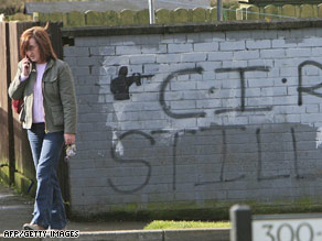  A woman walks past a wall on Tuesday sprayed with “C IRA still at war” in Craigavon, Northern Ireland.