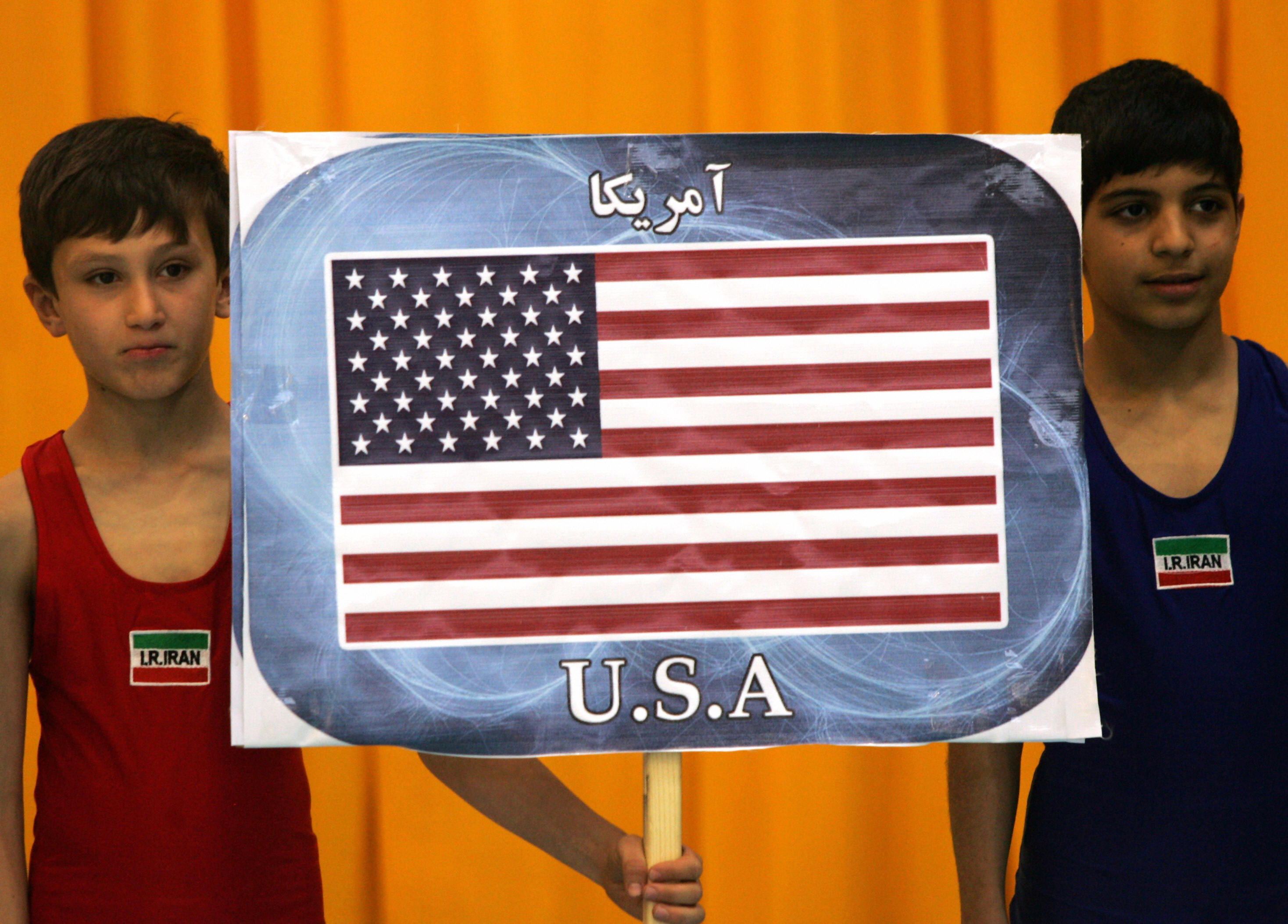 BEHROUZ MEHRI/AFP/Getty Images. Iranian boys hold a placard bearing the US flag to represtent the American team competing in the 29th international 'Takhti Cup' wrestling tournament during the opening ceremony in Tehran on March 12, 2009.