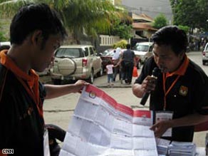 Indonesian election officials with a voting paper.