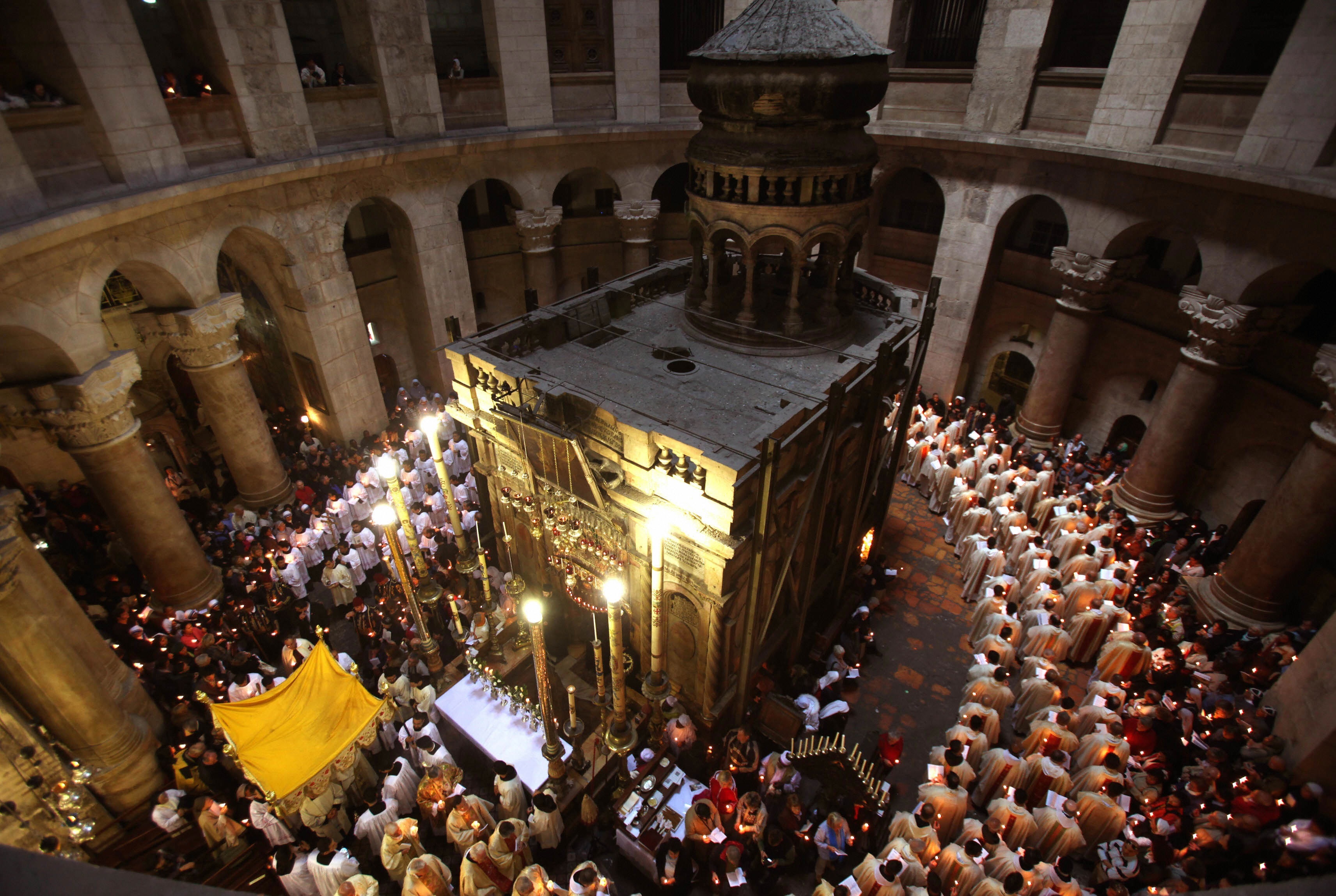 GALI TIBBON/AFP/Getty Images. Roman Catholic clergy men hold candles as they circle the aedicule during the Holy Thursday Easter procession at the Church of the Holy Sepulchre in Jerusalem's Old City on April 09, 2009. Christian believers around the world mark the solemn period of Easter in celebration of the crucifixion and resurrection of Jesus Christ. Christians traditionally believe the church is built on the site where Jesus was crucified and buried.