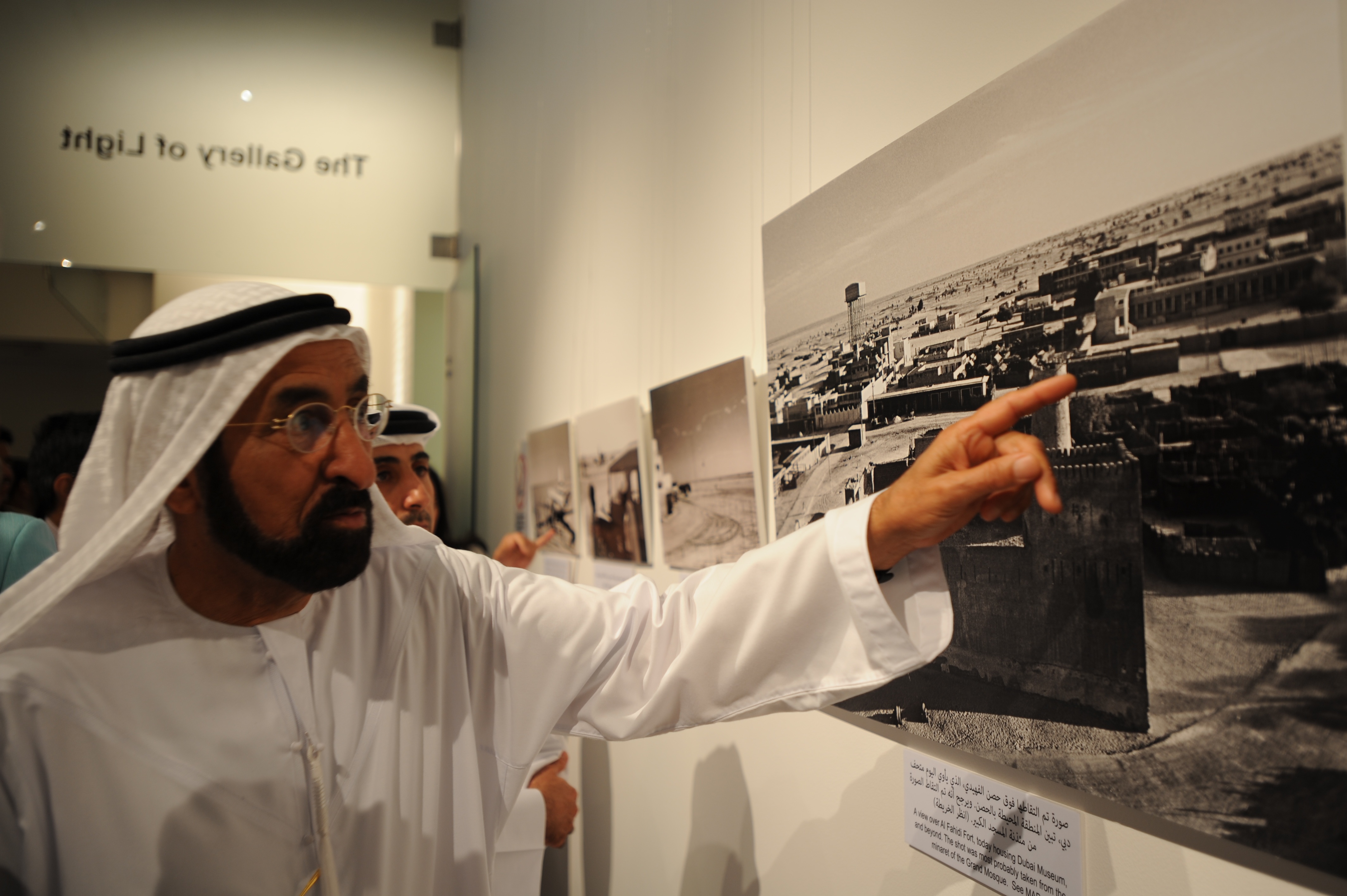 Jieun Lee/CNN. Mr. Juma Al Bawardi pointing at an old photo of Dubai’s skyline dominated by wind tower