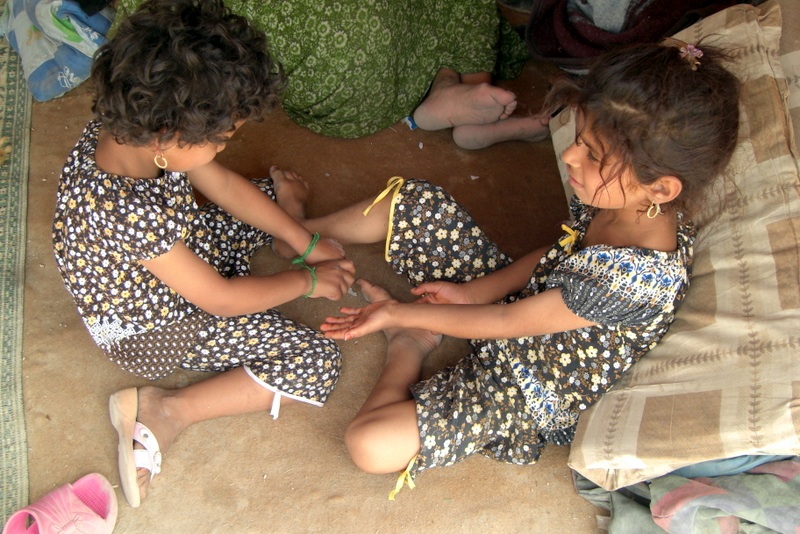 Mohammed Tawfeeq/CNN. Two sisters play inside a tent at Taji refugee camp