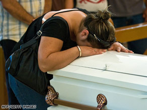 An unidentified mother collapses with grief on the coffin of her child on Sunday in Hermosillo, Mexico.