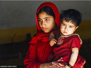 Saima, age 12, carrying her 10-month-old sister Sana. They walked 20 kms across mountain paths to escape fighting in their village.