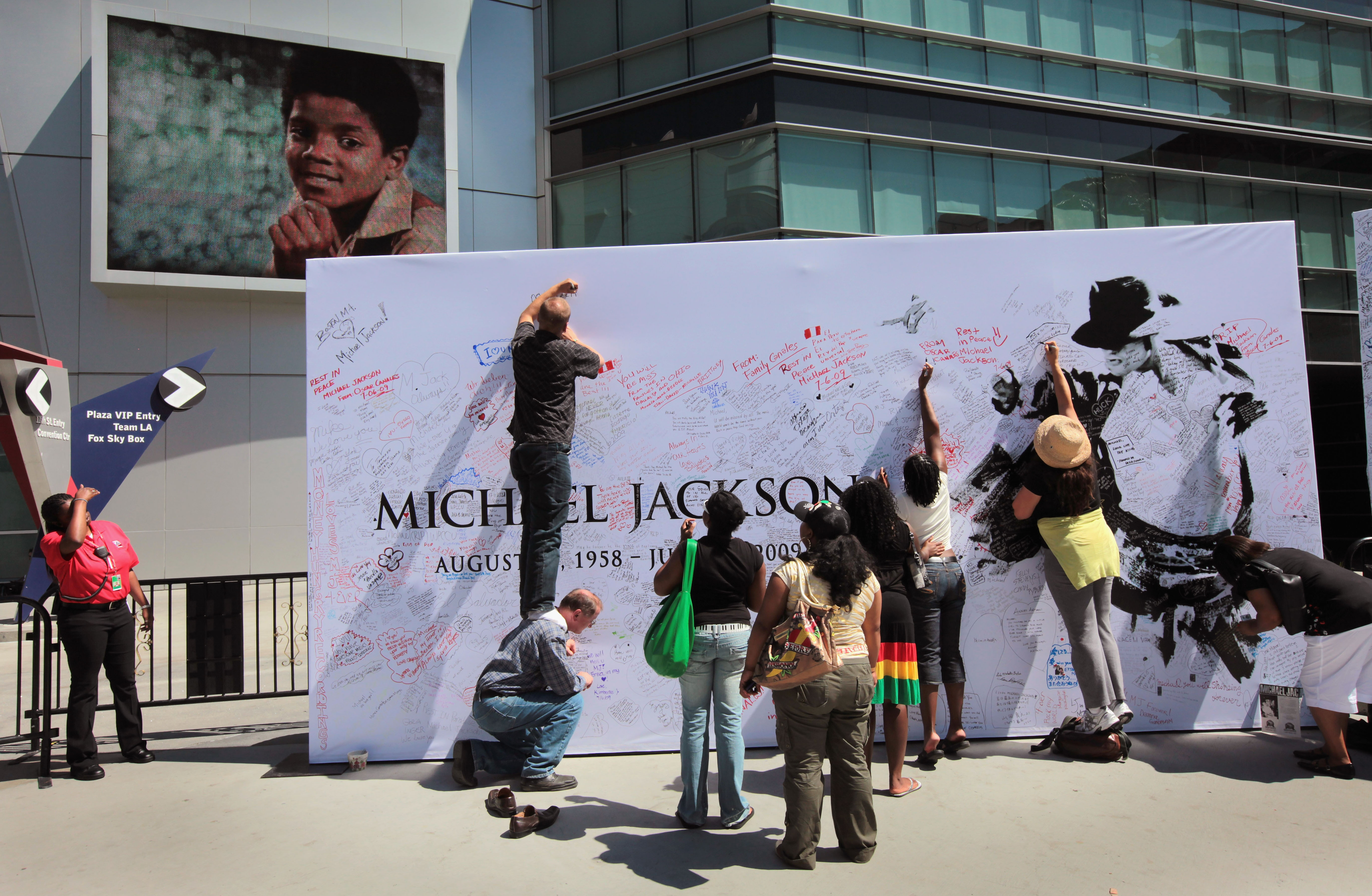 (Getty Images) Fans sign a Michael Jackson poster covered in messages outside the Staples Center.