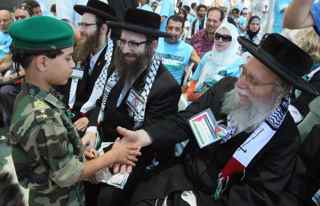 MAHMUD HAMS/AFP/Getty Images. A Palestinian boy wearing a security officer outfit shakes hands with a US member of the anti-Zionist religious Jewish community Naturei Karta during their visit to Gaza City on July 16, 2009. The group entered the Palestinian enclave late on July 15 with tens of foreign and Arab activists and an aid convoy headed by British MP George Galloway.