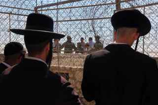 MENAHEM KAHANA/AFP/Getty Images. UN soldiers stand next to Lebanese onlookers (back) as they gather opposite ultra-Orthodox Jews praying during a visit to the site which they believe to be Rabbi Ashi's tomb, divided by a border electric fence, along northern Israel's border with Lebanon near Kibbutz Manara on August 4, 2009. The border fence passes right through the centre of the disputed tomb, which Israel considers to be the burial place of Rabbi Ashi but Lebanon says another man, Shiite cleric Sheikh Abbad, is buried there.