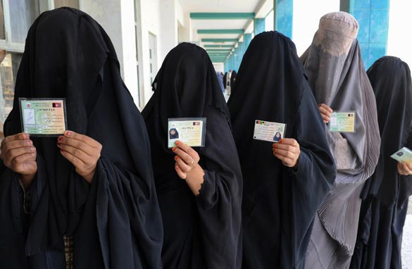 Burqa-clad Afghan women show identification cards as they wait to cast their votes at a school converted to a polling center in Kandahar on August 20, 2009. (Photo: BANARAS KHAN/AFP/Getty Images)