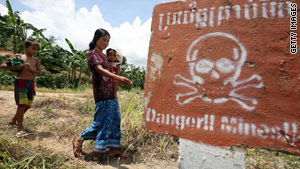  A Cambodian woman walks past a landmine awareness sign near the Thai border in July 2007.