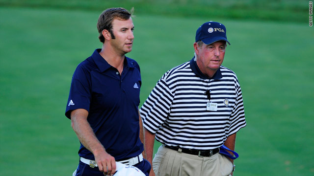 Dustin Johnson walks off on the 18th accompanied by a PGA rules official.