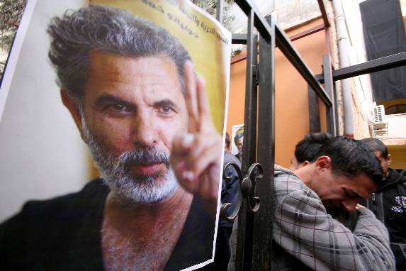 Palestinian youths mourn the death of Arab-Jewish actor and director Juliano Mer-Khamis (poster) outside The Freedom Theatre in Jenin refugee camp in the West Bank