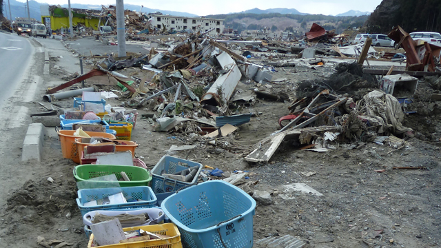 Hundreds of photos sit in baskets by the side of the road in the destroyed Japanese town of Minamisanriku.