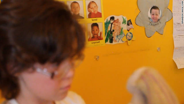 Tammy plays with a doll in her bedroom, where she has a picture of Thomas on her wall. 