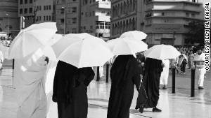 A Reem Al Faisal shot of people using umbrellas to protect them from the sun