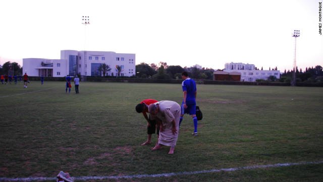 Members of the Libyan team's backroom staff pray after training.