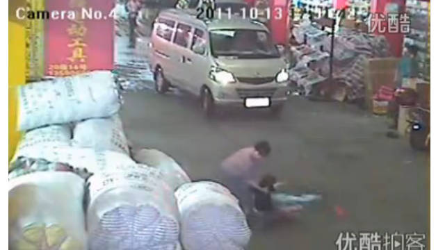 A screen grab of an incident on a China street where a toddler was run down shows a rescuer finally helping her