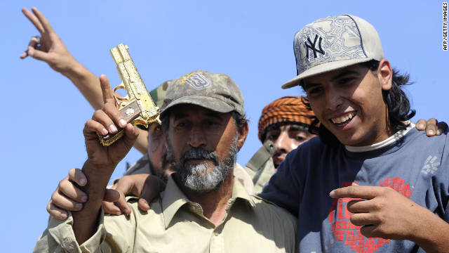 NTC fighters hold what they say is the ousted Libyan leader's gold-plated gun Thursday.