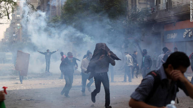 Protesters cover their faces as they flee tear gas fired by police on Sunday.