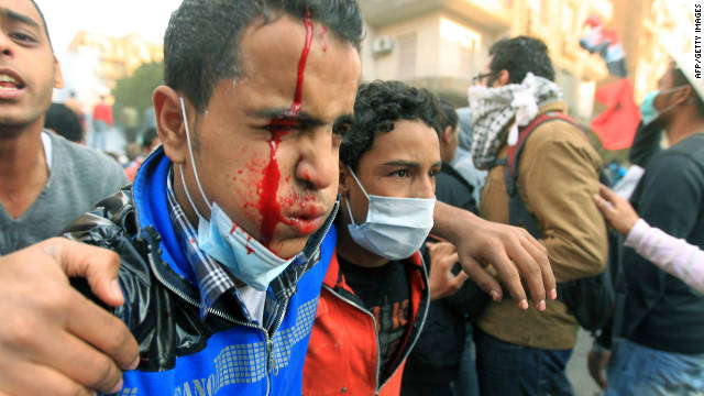 A protester bleeds as he is helped away from fighting Monday in Tahrir Square.