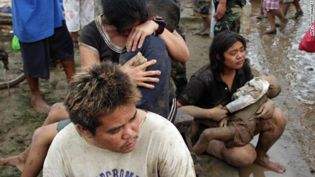 Two mothers hold the bodies of their children Saturday at a village in Iligan City.