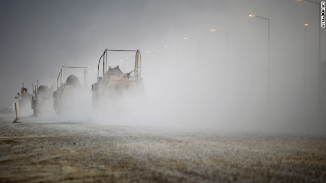 U.S. Mine Resistant Ambush Protected (MRAP) vehicles drive through Camp Adder before departing what is now known as Imam Ali Base on December 16.