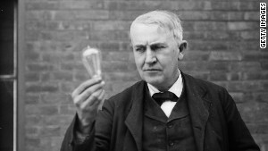 Inventor and physicist Thomas Alva Edison looking at a light bulb