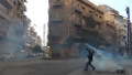 A protester in the flahspoint central Syrian city of Homs throws a tear gas bomb back towards security forces, on December 27, 2011. 
