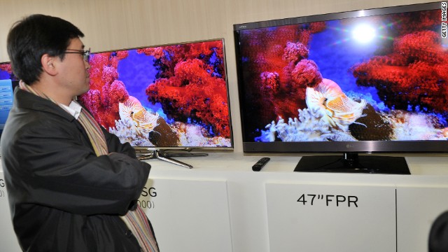 A journalist compares the 3-D televisions of Samsung (L) and LG (R) after a news briefing in Seoul. 