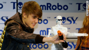 Justin Bieber holds a microphone in front of the mRobo Ultra Bass as he unveils the portable speaker and dancing robot.