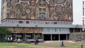 Students and families lounge on the grass outside the Central Library at the National Autonomous University of Mexico.