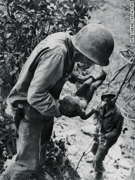 An American soldier comforts a wounded infant in Saipan.